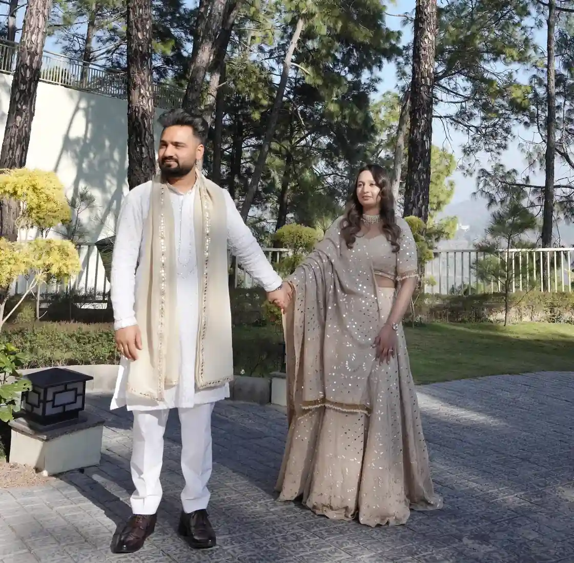 Couple in traditional Indian wedding attire holding hands outdoors